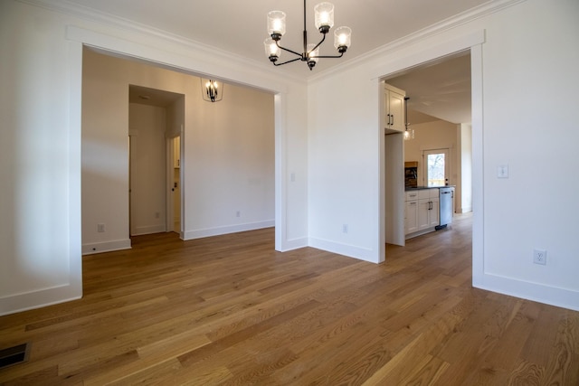 interior space featuring visible vents, baseboards, a notable chandelier, wood finished floors, and ornamental molding