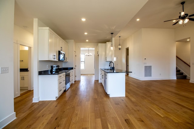 kitchen with dark countertops, open floor plan, stainless steel appliances, and a sink
