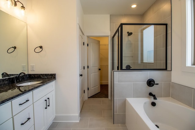 bathroom with a shower stall, tile patterned flooring, vanity, a bath, and baseboards