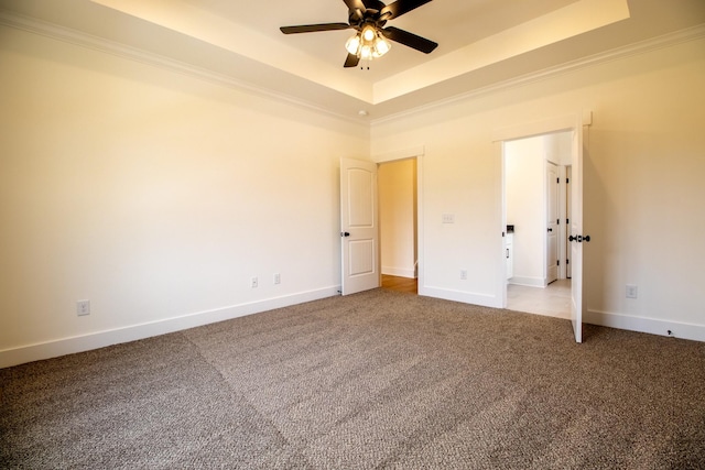 unfurnished bedroom with a tray ceiling, crown molding, carpet flooring, and baseboards