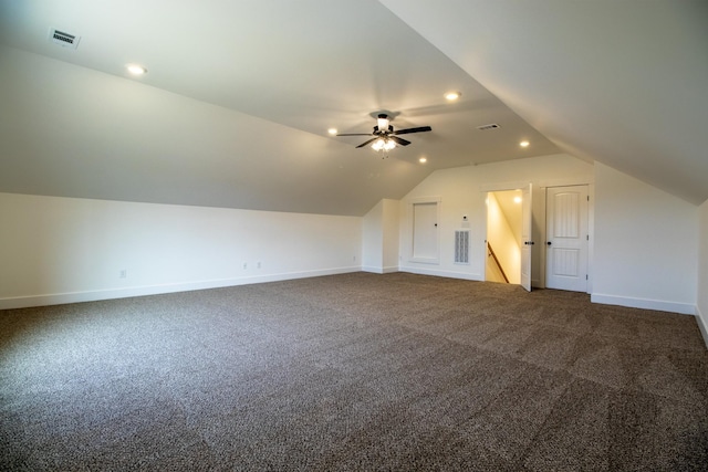additional living space featuring dark carpet, vaulted ceiling, and baseboards