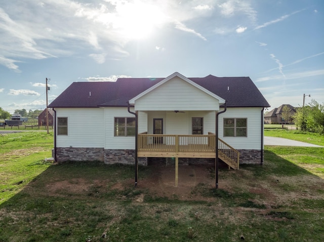 back of property featuring a ceiling fan, roof with shingles, a yard, and a deck