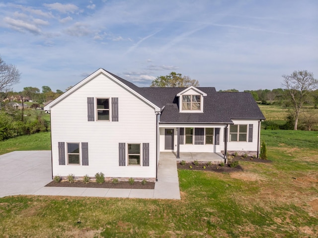 back of property with a lawn, roof with shingles, and a patio area