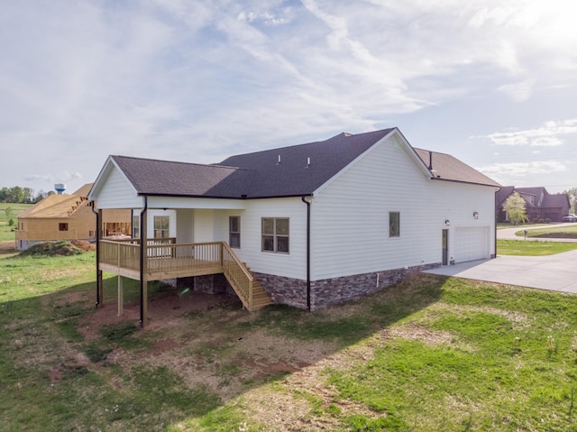 back of property with concrete driveway, stairway, a shingled roof, and a lawn