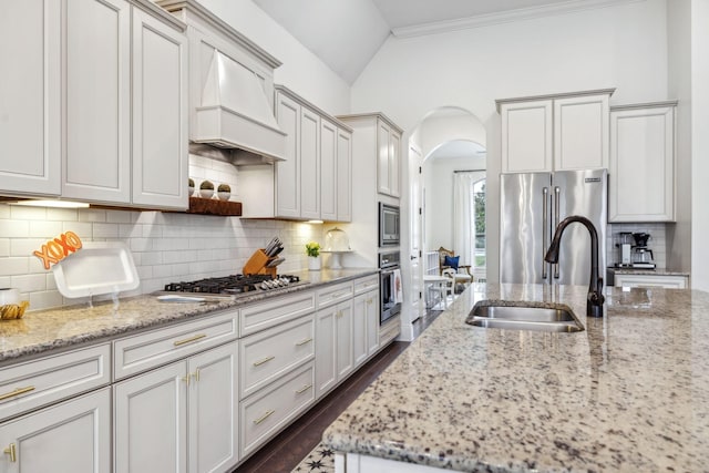 kitchen featuring stainless steel appliances, premium range hood, sink, and light stone counters