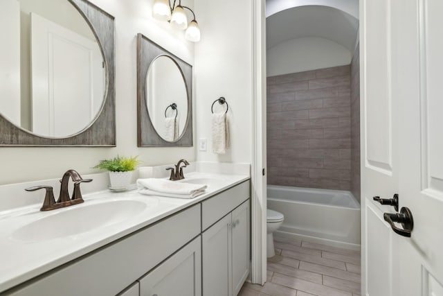 full bathroom with tiled shower / bath, vanity, and toilet