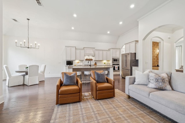 living room with ornamental molding, sink, hardwood / wood-style floors, and a notable chandelier