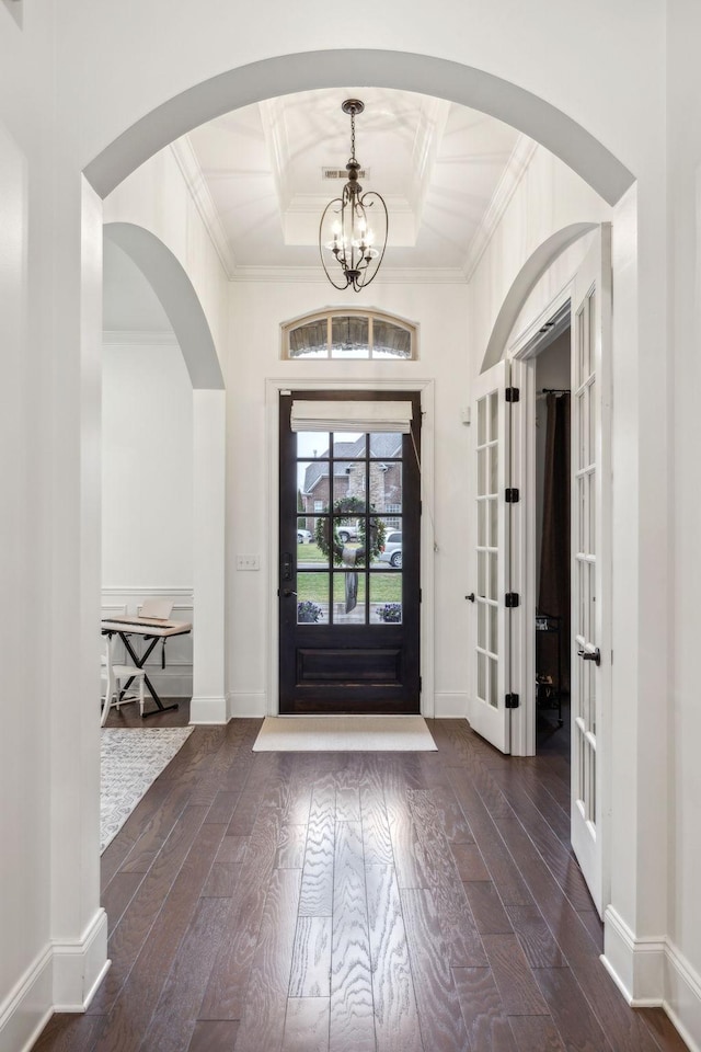 foyer with a notable chandelier, ornamental molding, and dark hardwood / wood-style floors