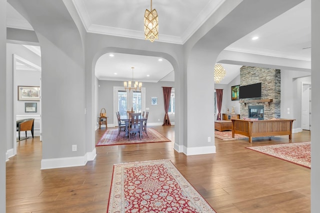 foyer entrance featuring crown molding, a fireplace, hardwood / wood-style floors, and a notable chandelier