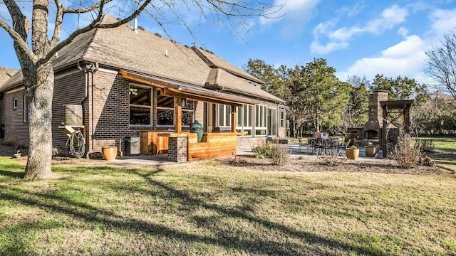 rear view of house with a patio, exterior bar, a yard, and a fireplace