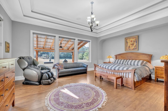 bedroom featuring a chandelier, ornamental molding, a raised ceiling, and light hardwood / wood-style flooring