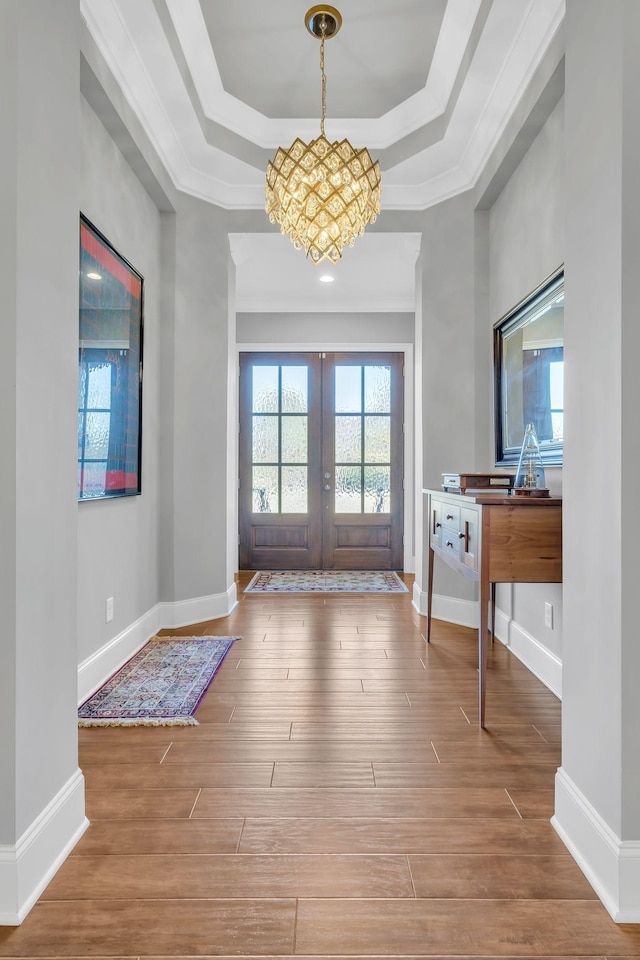 entryway featuring french doors, wood-type flooring, ornamental molding, and a tray ceiling