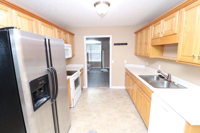 kitchen with white appliances, light brown cabinetry, and sink