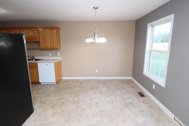 kitchen featuring pendant lighting, a wealth of natural light, stainless steel refrigerator, and dishwasher