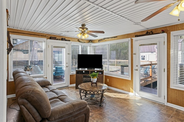 living room featuring ceiling fan and wood walls