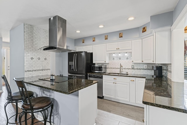 kitchen with white cabinetry, dark stone countertops, island range hood, black appliances, and kitchen peninsula