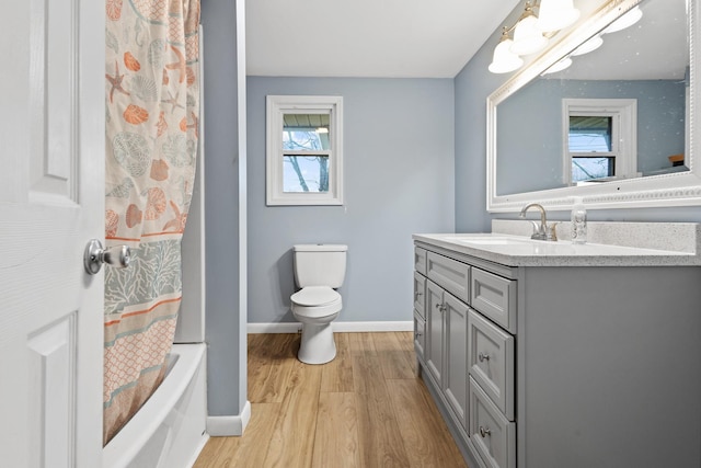 full bathroom with hardwood / wood-style flooring, vanity, shower / tub combo with curtain, and toilet