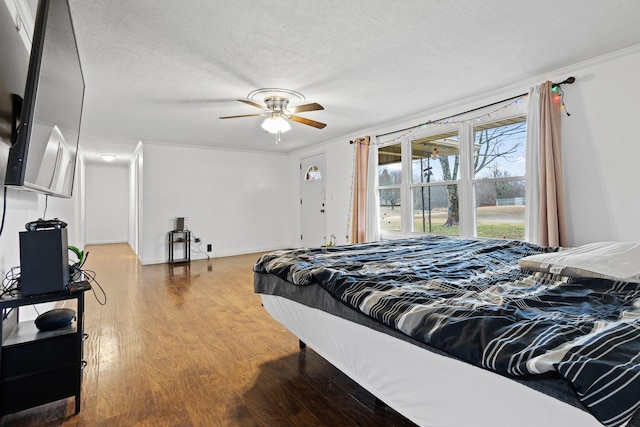 bedroom featuring hardwood / wood-style flooring, ceiling fan, crown molding, and a textured ceiling