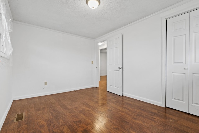 unfurnished bedroom featuring ornamental molding, dark wood-type flooring, a textured ceiling, and a closet