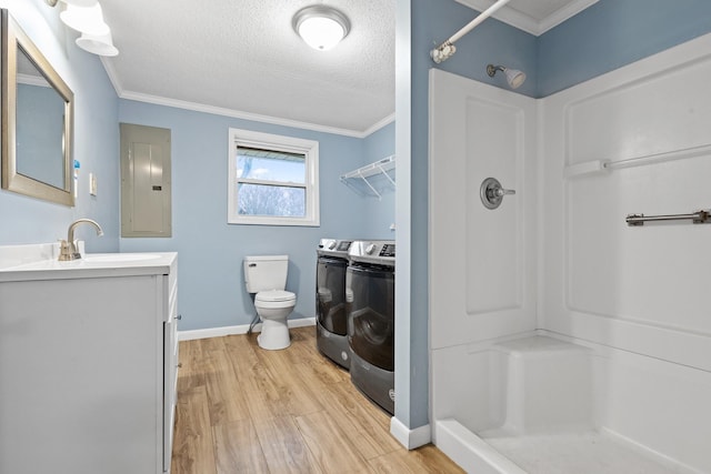 bathroom with washer and dryer, a shower, wood-type flooring, ornamental molding, and electric panel