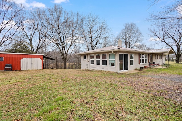 rear view of house featuring a lawn and an outdoor structure