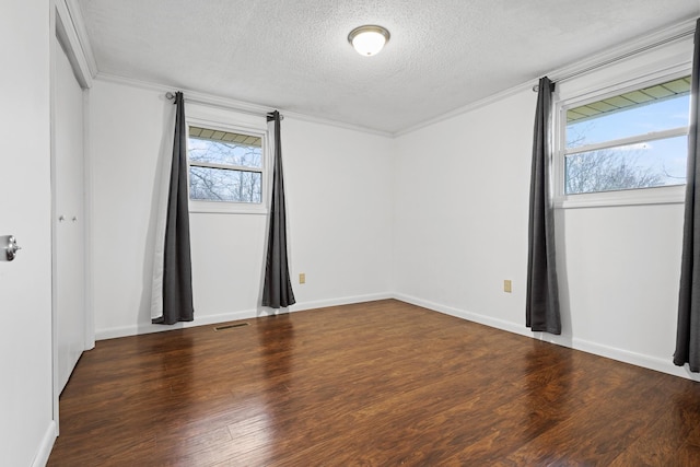 unfurnished room with dark hardwood / wood-style flooring, ornamental molding, and a textured ceiling