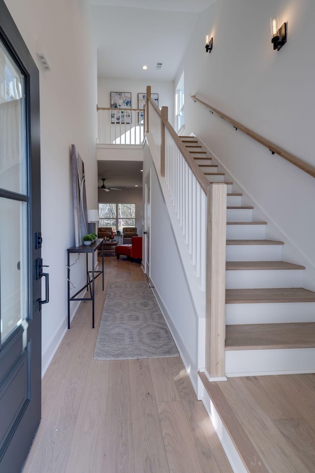 foyer with a towering ceiling and light wood-type flooring