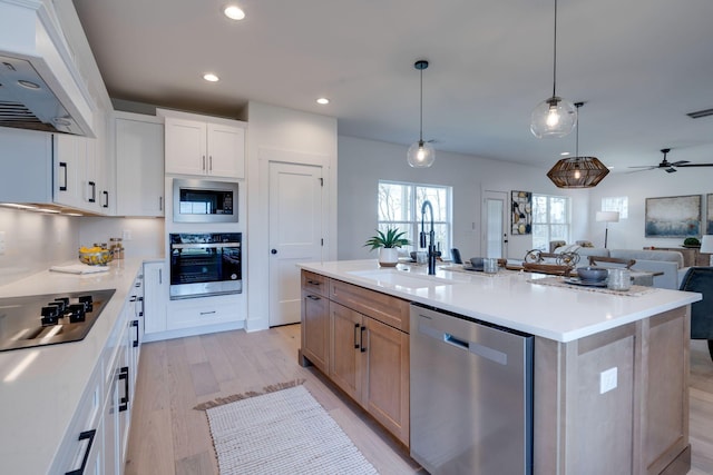 kitchen featuring sink, white cabinetry, a center island with sink, appliances with stainless steel finishes, and pendant lighting