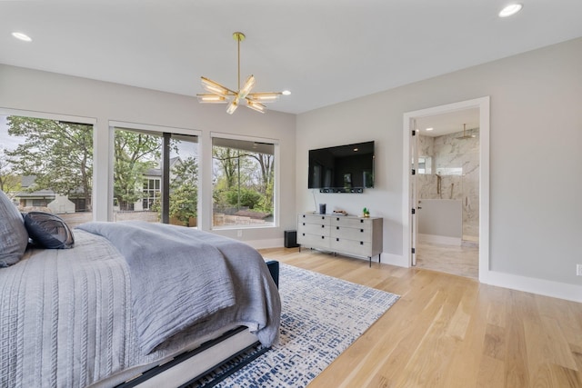 bedroom featuring an inviting chandelier, light hardwood / wood-style flooring, and ensuite bathroom