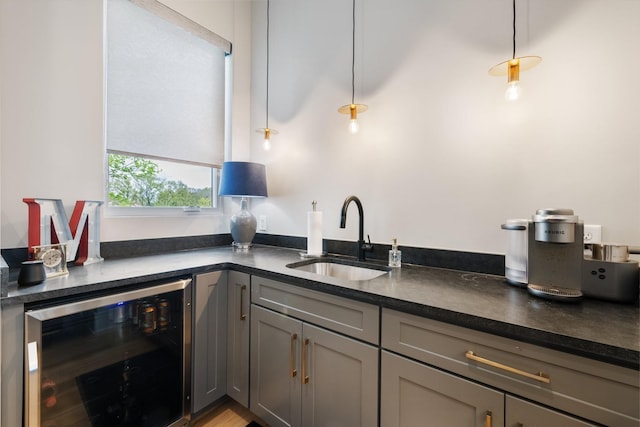 kitchen with sink, gray cabinetry, beverage cooler, and decorative light fixtures