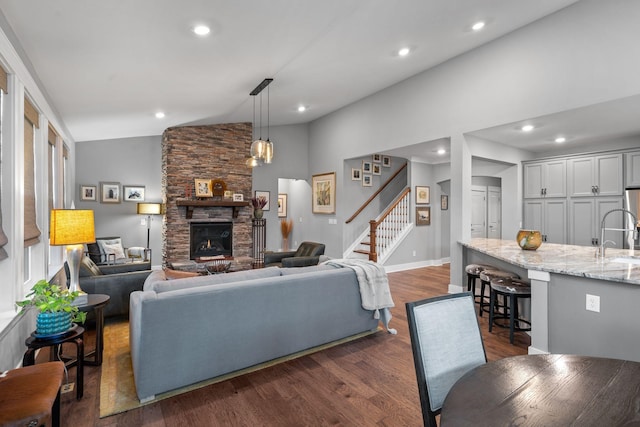 living room featuring vaulted ceiling, dark hardwood / wood-style flooring, sink, and a fireplace