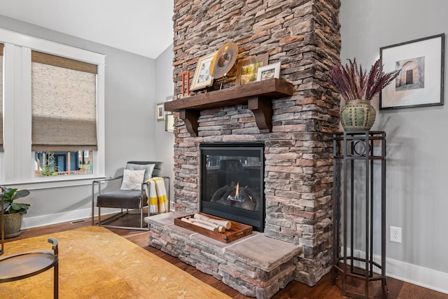 living room with dark hardwood / wood-style flooring, a stone fireplace, and vaulted ceiling