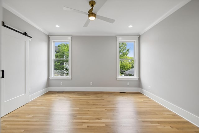 unfurnished bedroom with multiple windows, ornamental molding, and a barn door