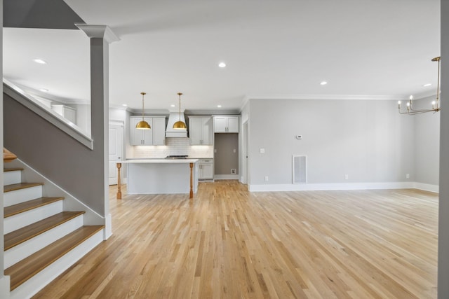 unfurnished living room featuring ornamental molding, a chandelier, and light wood-type flooring