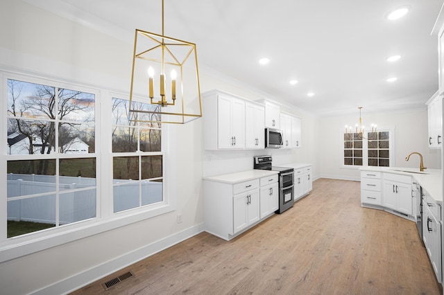 kitchen featuring white cabinetry, appliances with stainless steel finishes, a chandelier, and pendant lighting