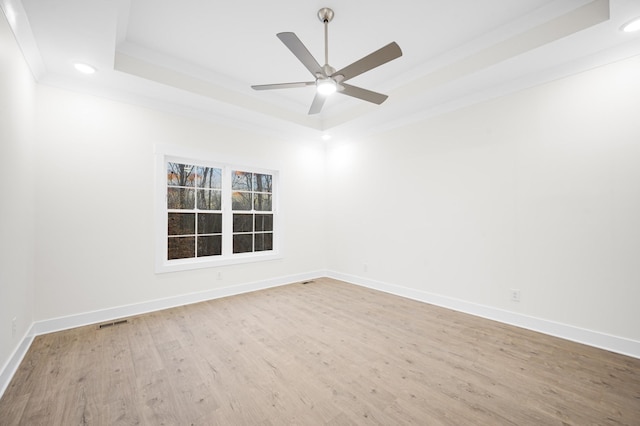 empty room with hardwood / wood-style flooring, ornamental molding, ceiling fan, and a tray ceiling