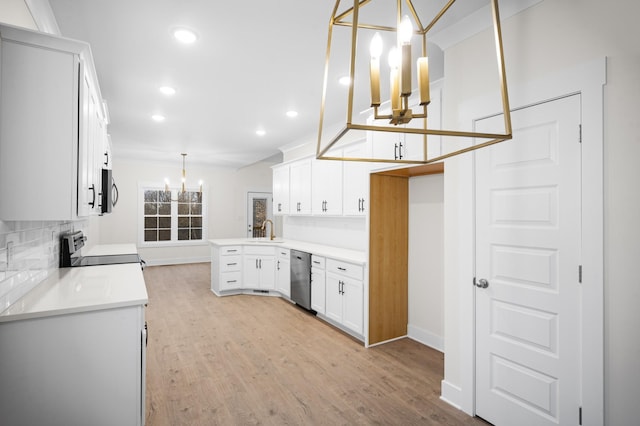 kitchen with sink, white cabinetry, an inviting chandelier, hanging light fixtures, and stainless steel appliances