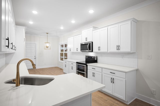 kitchen featuring white cabinetry, appliances with stainless steel finishes, sink, and decorative light fixtures