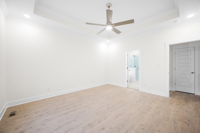 unfurnished room featuring ornamental molding, ceiling fan, light hardwood / wood-style floors, and a tray ceiling