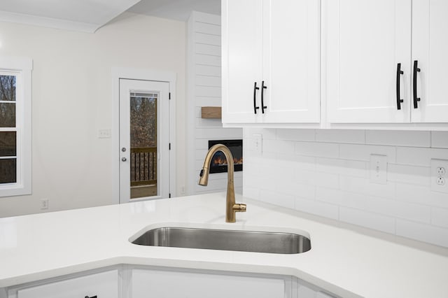 room details featuring sink, white cabinets, and decorative backsplash