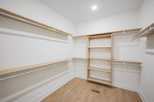 walk in closet with light hardwood / wood-style floors