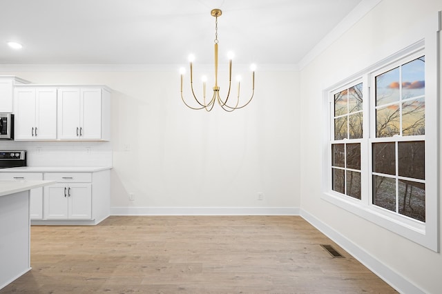 unfurnished dining area featuring a notable chandelier, crown molding, and light hardwood / wood-style flooring