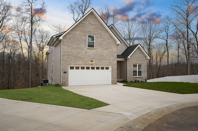 front of property with central AC, a garage, and a yard