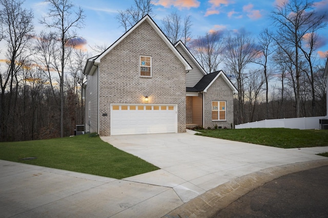 view of front property with a garage, a yard, and central AC unit