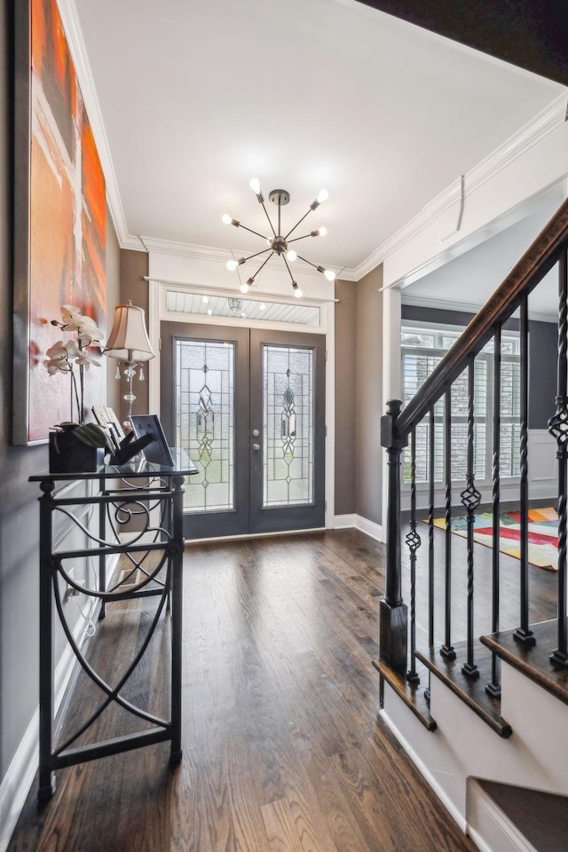 foyer entrance with hardwood / wood-style flooring, ornamental molding, french doors, and a notable chandelier