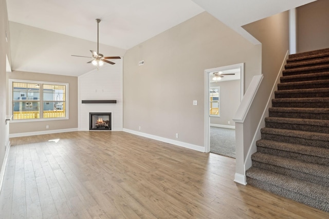 unfurnished living room with hardwood / wood-style flooring, ceiling fan, lofted ceiling, and a fireplace