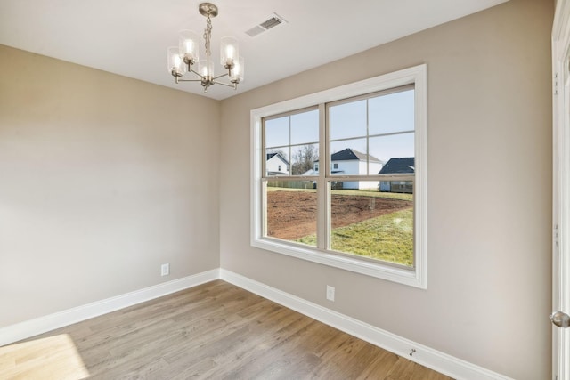 unfurnished room featuring an inviting chandelier and light hardwood / wood-style flooring