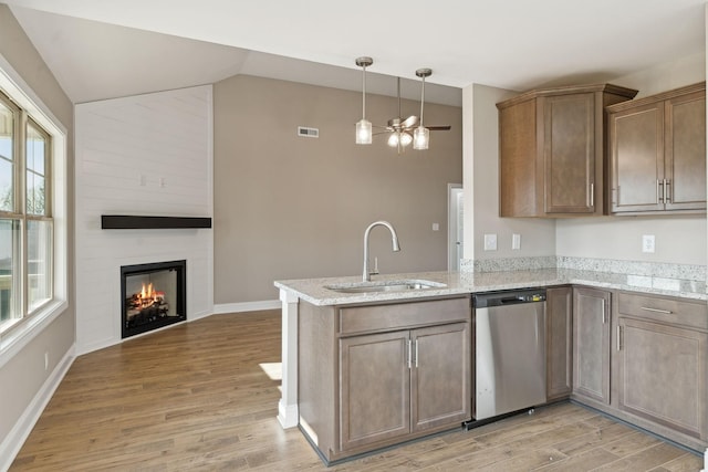 kitchen with vaulted ceiling, sink, hardwood / wood-style flooring, stainless steel dishwasher, and kitchen peninsula