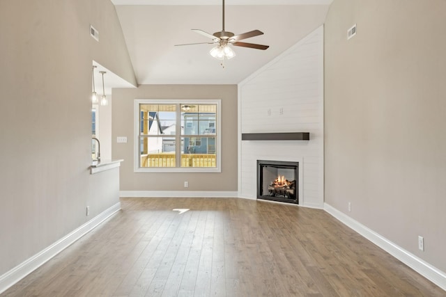 unfurnished living room featuring ceiling fan, wood-type flooring, a fireplace, and high vaulted ceiling