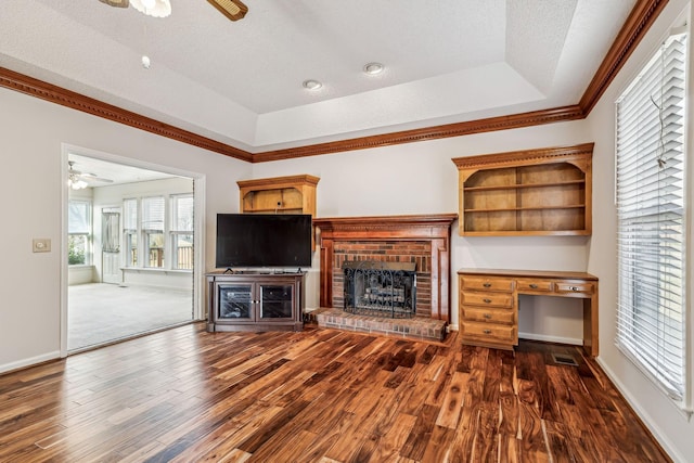 unfurnished living room featuring ceiling fan, dark hardwood / wood-style floors, a raised ceiling, and a fireplace